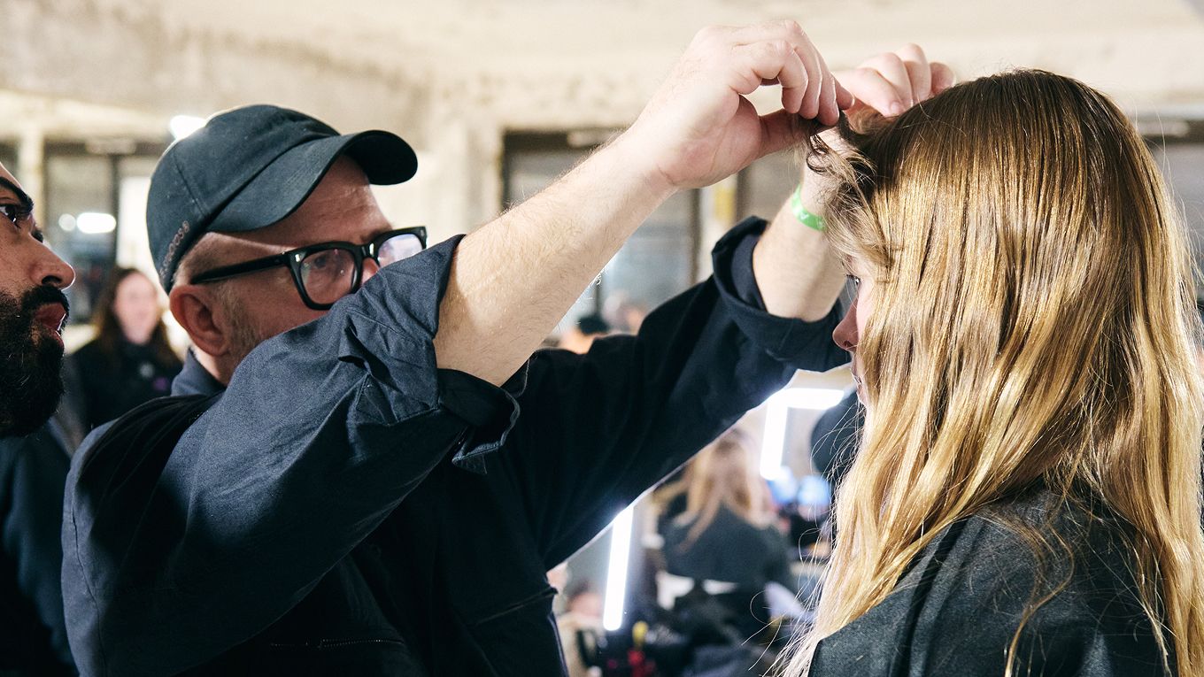 A professional stylist adds the finishing touches to a model’s hairstyle.